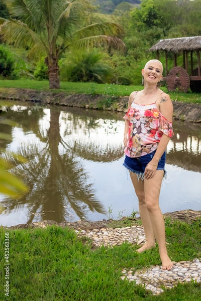 Obraz Beautiful and strong woman fighting breast cancer Smiling and happy. Hairless and bald. live and joy of fighting. Smile on the lake and on the ranch.