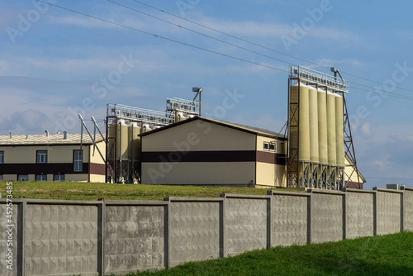 Fototapeta Agro-industrial complex for processing plant products on a hill against a blue sky.
