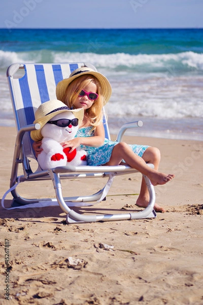 Fototapeta девочка сидит на шезлонге на берегу моря