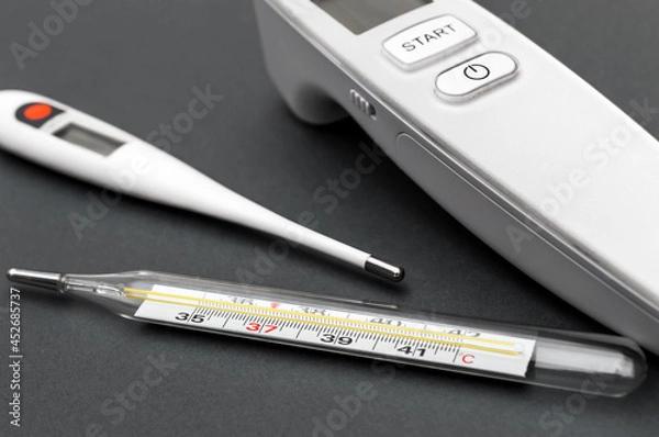 Fototapeta Different type of thermometers on grey background. Infrared, electronic and mercury thermometers.