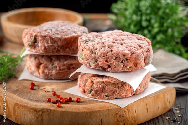 Obraz Frozen spicy pork patties with seasonings on table. Butcher minced meat cutlet, close up