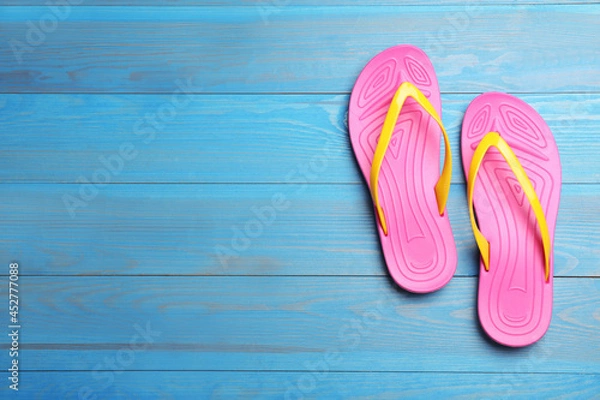 Fototapeta Stylish beach flip flops on blue wooden background, flat lay. Space for text