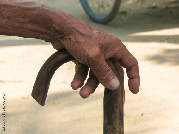 Fototapeta Indian Elderly Man kept his hand on walking cane on the street in the village of Bangladesh