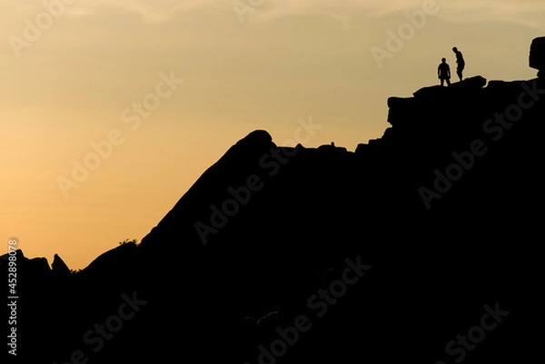 Fototapeta Two rock climbers look back from the summit of stanage edge in england