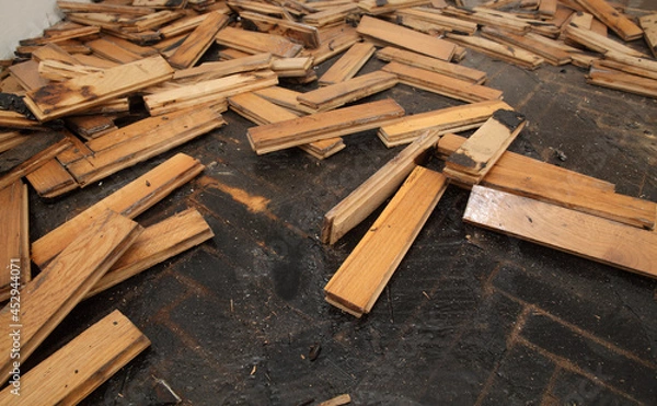 Fototapeta Old damaged parquet removal, heap of small planks at bitumen covered floor