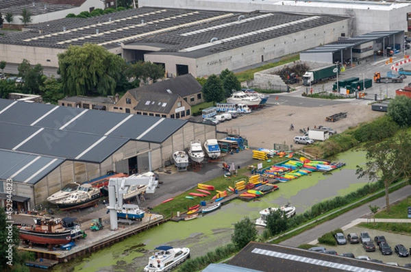 Fototapeta Diksmuide, Flanders, Belgium - August 3, 2021: Aerial view on canoe producing and renting out business along Yser river in industrial zone, SE from IJzertoren.