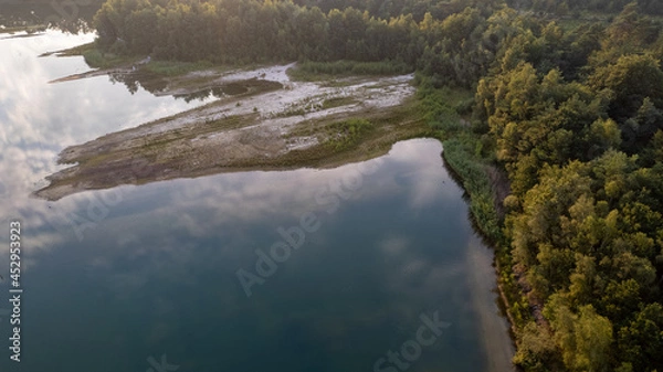 Fototapeta Aerial view shot by a drone of the shore of a forest lake. Thick grass, reflections in the water, green birches in the distance on the slope. Nature of the Blakheide, Beerse, Belgium. High quality