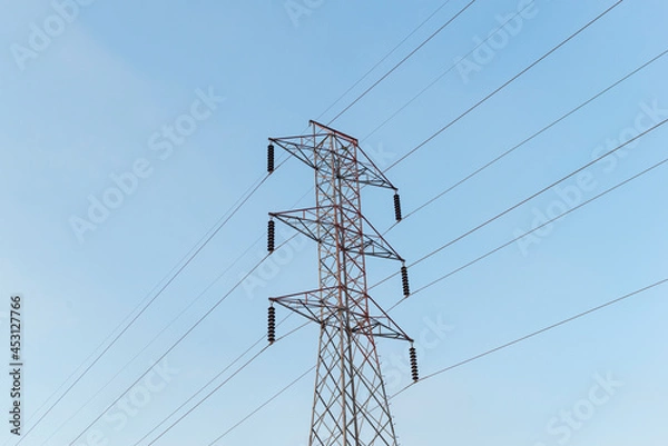 Fototapeta High-voltage power lines electricity transmission pylon on blue sky background.
