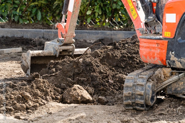 Fototapeta Bagger arbeitet mit Erdboden im Garten