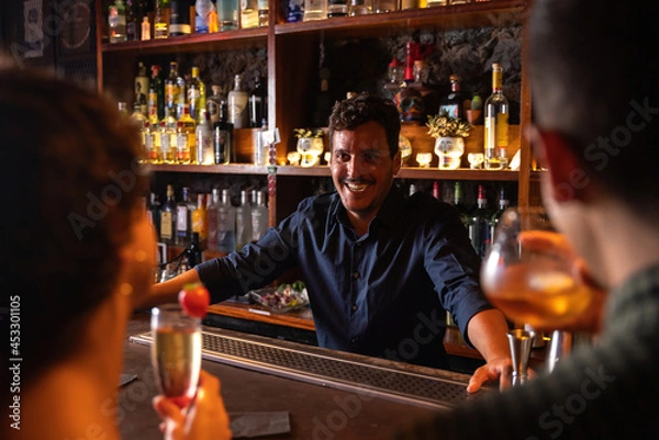Obraz bartender chatting with customers while enjoying cocktails
