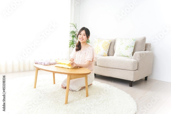 Fototapeta 洗濯物をたたむ若い女性
