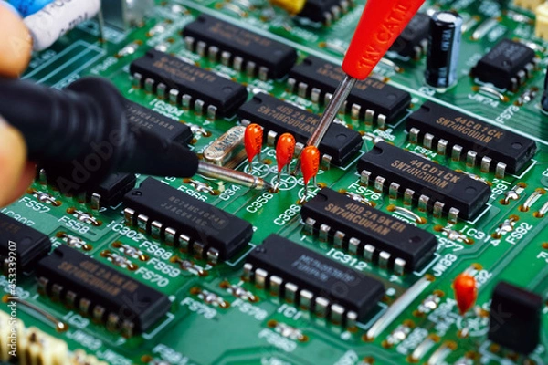 Fototapeta The hand of the engineer measures the voltage on the electrical board with the test leads of the multimeter. Closeup.	