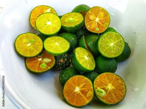 Fototapeta sliced ​​green oranges placed on a white plate