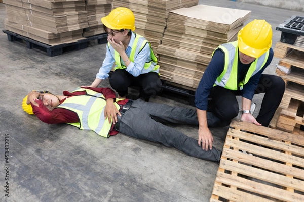 Obraz man factory worker have a leg accident from wooden crate and lying on the floor