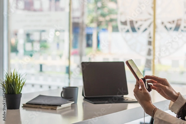 Fototapeta businesswoman is using a smartphone to communicate and check work from home online because she is starting a business that can order and check from anywhere online.online business ideas