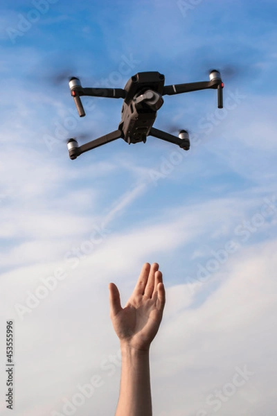 Obraz a tourist guy launches a quadrocopter and reaches for it with his hand