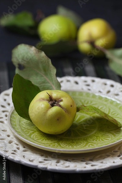 Fototapeta Quitten mit Blättern auf Teller und dahinter