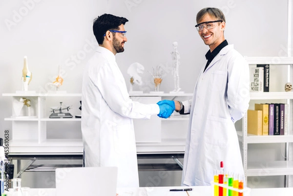 Obraz Professional two scientist man research and working doing a chemical experiment while making analyzing and mixing liquid in test tube.Young science man dropping sample chemical on glass at laboratory