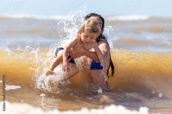 Obraz MÃE E FILHO BRINCANDO NAS ONDAS DA PRAIA.
