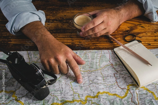 Fototapeta Detail of a man hand pointing out a destination on a map