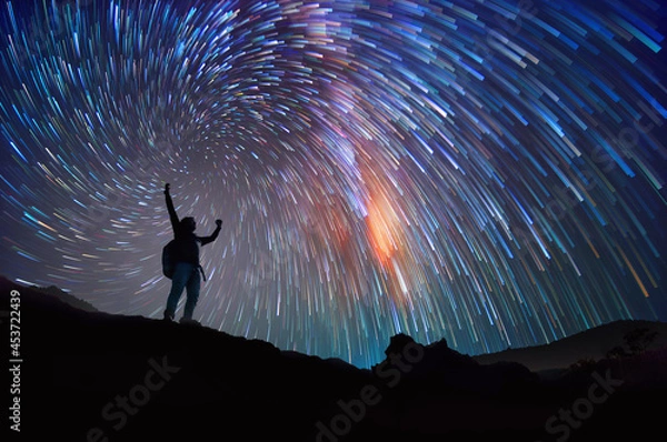 Fototapeta Landscape with Milky Way. Night sky with stars and silhouette of a standing happy man on the mountain, Success or winner, leader concept.  