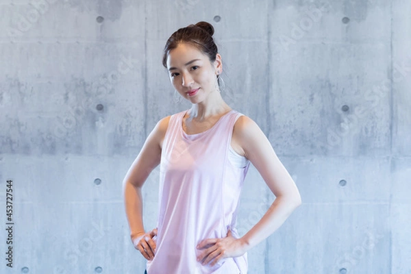 Fototapeta フィットネスクラブで壁の前に立っている女性