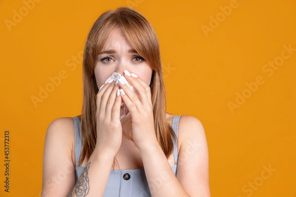 Fototapeta Portrait of young Caucasian girl has a cold isolated on yellow color studio background. Concept of human emotions, facial expression, health care, feelings, ad.