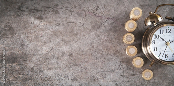 Fototapeta Stack of coins with alarm clock.