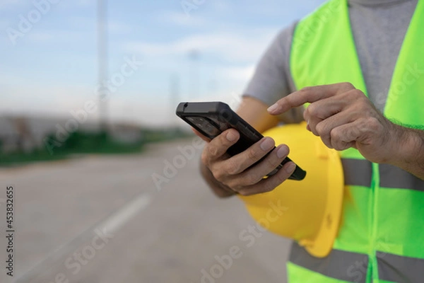 Fototapeta construction working on his smartphone at the construction site with copy space