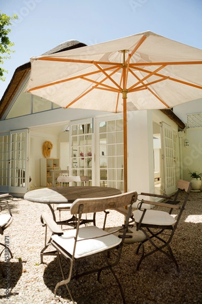 Obraz Chairs and table under umbrella in backyard