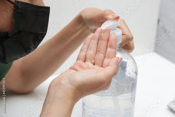 Fototapeta passando álcool com gel na mão para se proteger do covid19.
