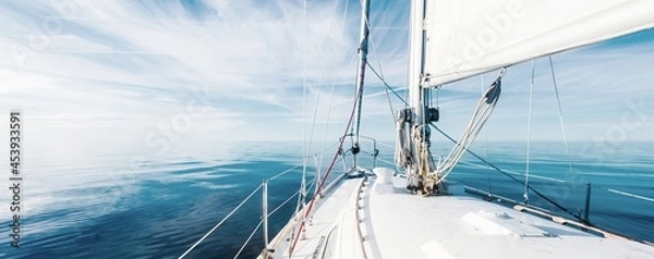 Obraz White sloop rigged yacht sailing in an open Baltic sea on a clear sunny day. A view from the deck to the bow, mast and sails. Estonia