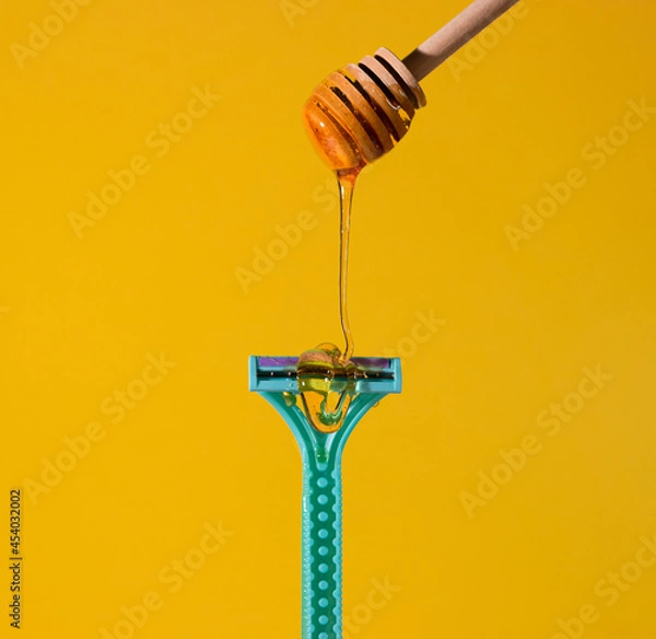 Obraz Sugar paste for hair removal against a razor. Sugaring paste drips on the razor. The concept of epilation, spa, body care.