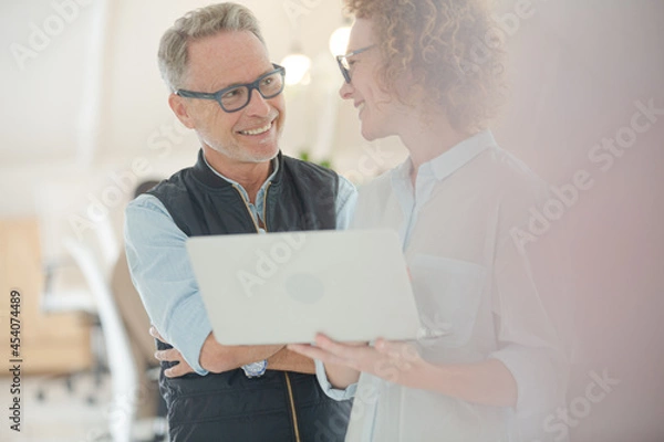 Fototapeta Portrait of man and woman with laptop, smiling in office