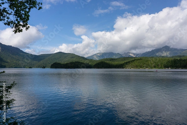 Obraz Ein blauer See. Im Hintergrund sind Berge und am Himmel Wolken.