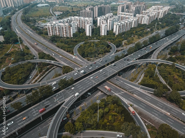 Fototapeta Top up aerial drone view of elevated road and traffic junctions in Chinese metropolis city during sunny day golden hour. Modern construction design of traffic ways to avoid traffic jams. Few vehicles.