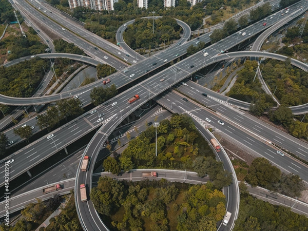 Fototapeta Top up aerial drone view of elevated road and traffic junctions in Chinese metropolis city during sunny day golden hour. Modern construction design of traffic ways to avoid traffic jams. Few vehicles.