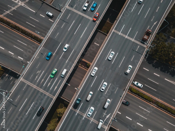 Fototapeta Top up aerial drone view of elevated road and traffic junctions in Chinese metropolis city during sunny day golden hour. Modern construction design of traffic ways to avoid traffic jams. Few vehicles.