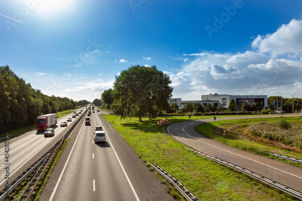 Fototapeta Cars and trucks driving on the A44 highway near the South-Holland village of Sassenheim in the township Teylingen in the Netherlands. At the Exit Hotel Sassenheim.