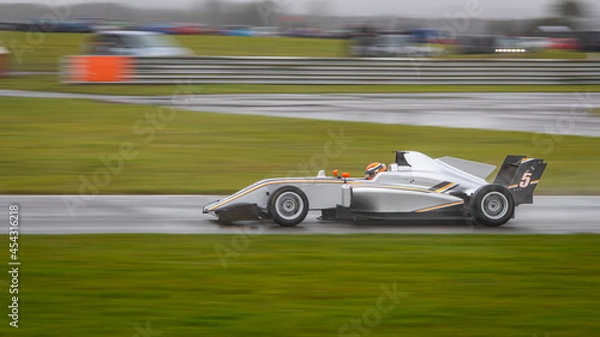 Fototapeta A panning shot of a racing car as it circuits a track.