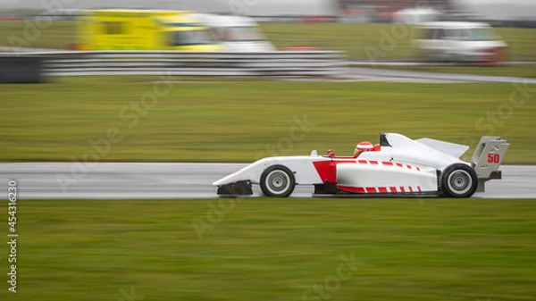 Fototapeta A panning shot of a racing car as it circuits a track.