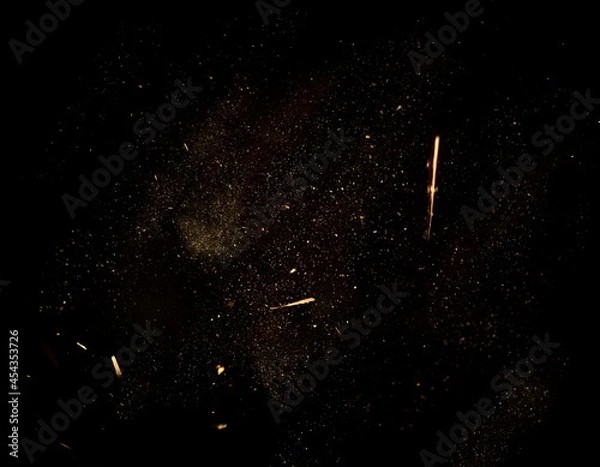 Fototapeta Dust and wood chips on a black background. Dirt particles fly in the air. Layout for design. Some dust particles are blurred to transmit the effect of motion.