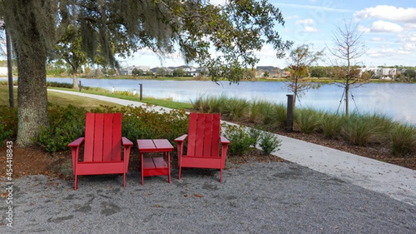 Obraz Two chairs sitting in a park by a lake in Laurete Park in Lake Nona, Orlando, FL on a beautiful sunny day.