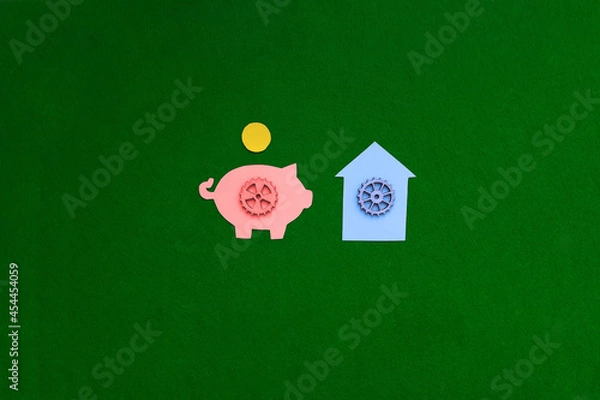 Fototapeta Piggy bank, gear house on a green background. The housing market. Purchase, sale of non-movable property.