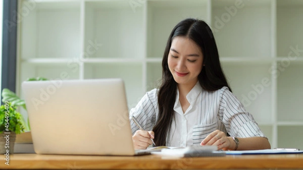 Fototapeta Happy and Charming business employee working in office, taking notes