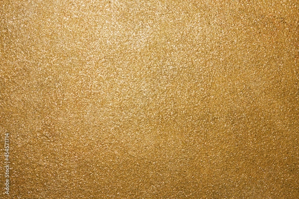Fototapeta Golden rough surface covered with sequins. Beautiful festive pattern for holidays. Backdrop for Christmas text. Horizontal photo.