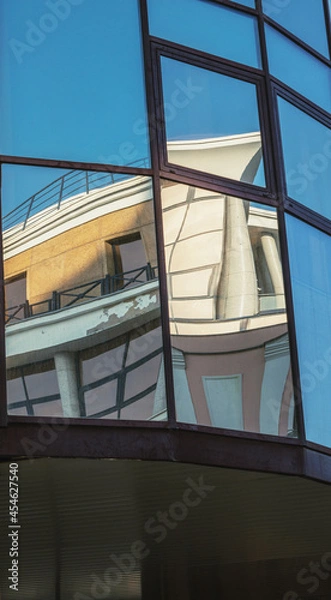Fototapeta Reflections in the windows of buildings in the city close up