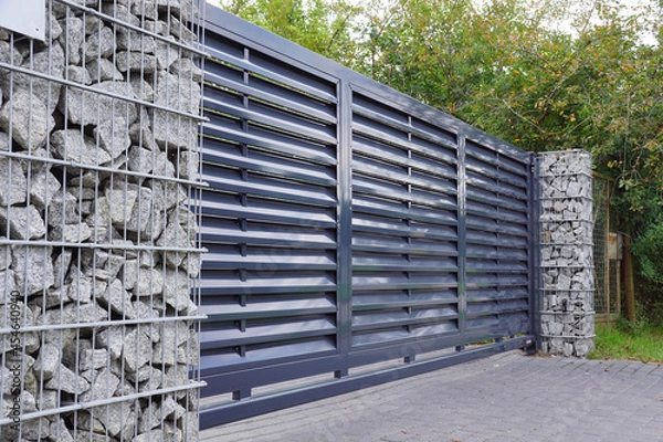 Fototapeta Gabion. Automatic entrance gate used in combination with a wall made of gabion.