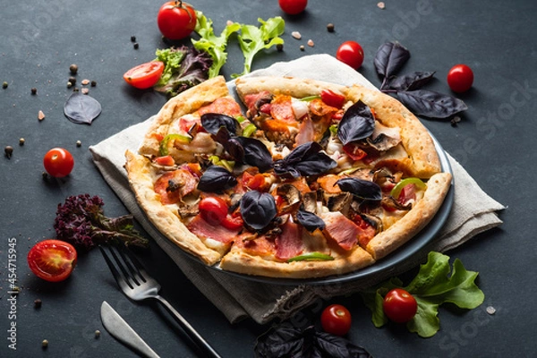 Fototapeta Savory Homemade Meat Pizza with Pepperoni, Bacon, tomatoes and basil on a dark background.