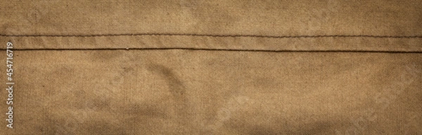 Fototapeta Wide panoramic surface texture of army rough khaki fabric with seam and dark vignette. Template for design and site header